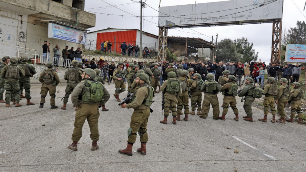 جنود إسرائيليون يقفون بين المستوطنين والسكان الفلسطينيين في قرية برقة في الضفة الغربية، 17 ديسمبر 2021. (أ ف ب)