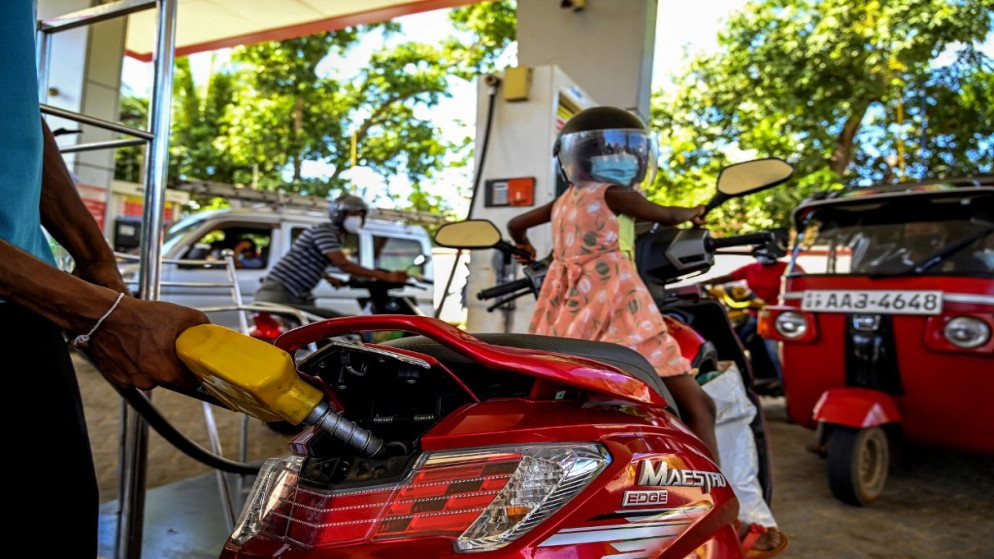 عامل يملأ خزان دراجة نارية بالبنزين في محطة بنزين في إمبيليبيتيا .21 ديسمبر 2021. ( أ ف ب)