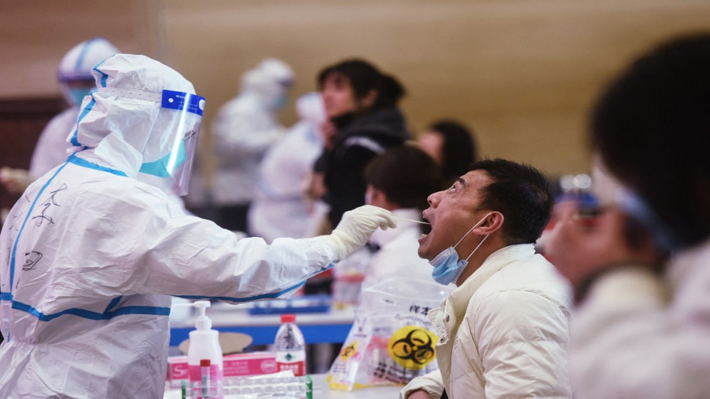 عامل طبي، يأخذ عينة مسحة من عامل خدمة لاختبار فيروس كورونا، شرق الصين، 15 كانون الأول/ديسمبر 2021. (أ ف ب)