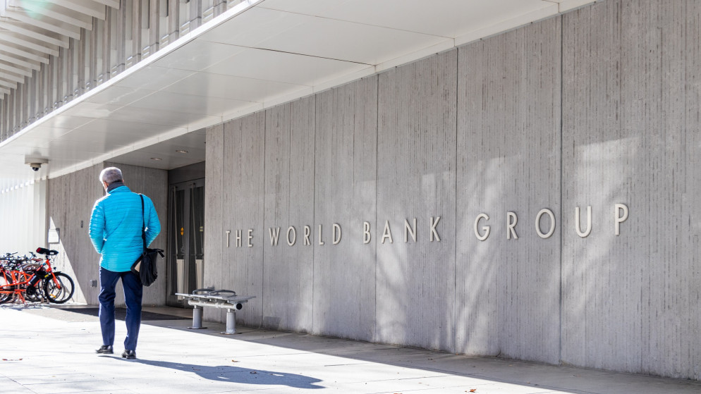 رجل يسير بجانب لافتة أمام مبنى مجموعة البنك الدولي في مقرها في واشنطن العاصمة الأميركية. (shutterstock)