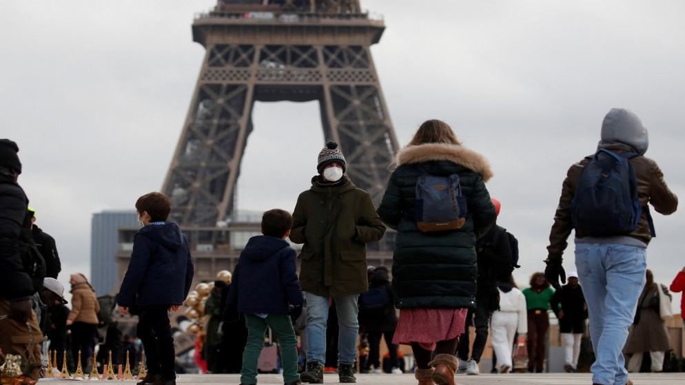 أشخاص يرتدون أقنعة واقية من كورونا يسيرون في ميدان تروكاديرو بالقرب من برج إيفل في باريس وسط تفشي مرض فيروس كورونا في فرنسا ، 6 ديسمبر / كانون الأول 2021. (رويترز)