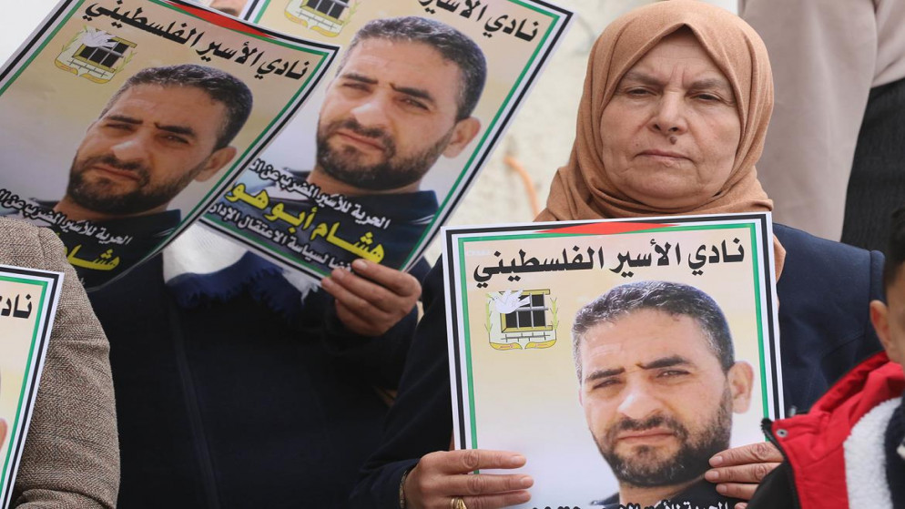 أشخاص يرفعون صور الأسير الفلسطيني هشام أبو هواش خلال وقفة في الخليل، (وفا)