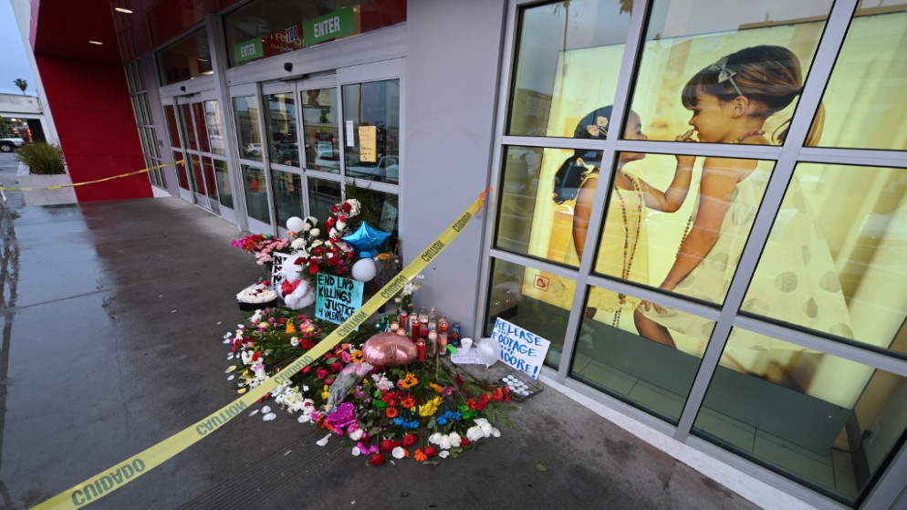 زهور على طول لافتة كتب عليها "أطلقوا سراح لقطات مور" في نصب تذكاري مؤقت للفتاة التي قتلت برصاصة طائشة للشرطة في مصنع معاطف في بيرلينجتون، شمال هوليوود، كاليفورنيا، 27 ديسمبر 2021. (أ ف ب)
