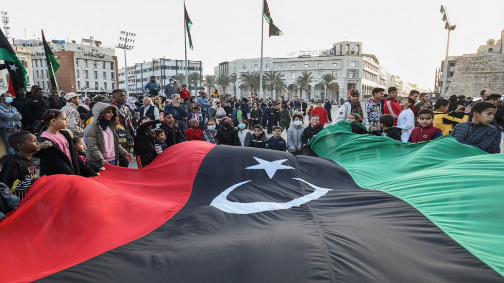 أطفال يلوحون بالعلم الوطني الليبي بينما يتجمع الناس في ساحة الشهداء في وسط العاصمة الليبية طرابلس للاحتفال بعيد الاستقلال السبعين للبلاد.24 ديسمبر 2021.(أ ف ب)