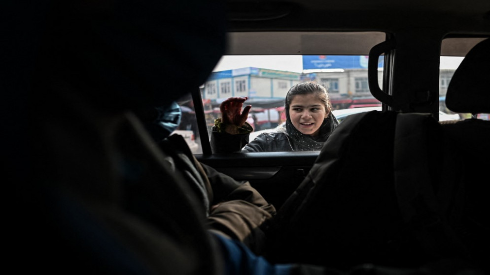 فتاة أفغانية تطلب المساعدة قرب مركبة في العاصمة الأفغانية كابل. 25 كانون الأول/ديسمبر 2021. (أ ف ب)