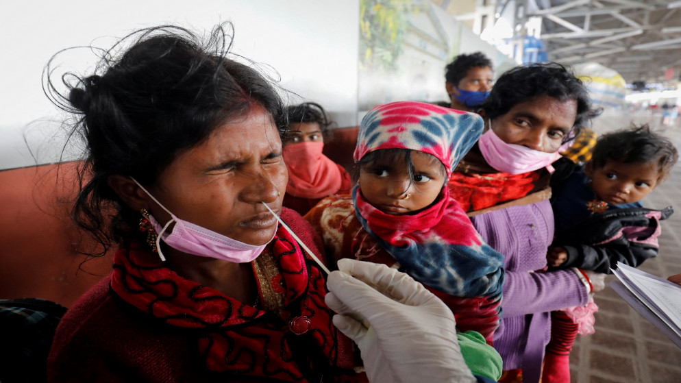 عاملة رعاية صحية تجري فحص الكشف عن كورونا لامرأة في محطة سكة حديد في أحمد آباد، الهند، 29 كانون الأول/ديسمبر 2021. (رويترز / أميت ديف)