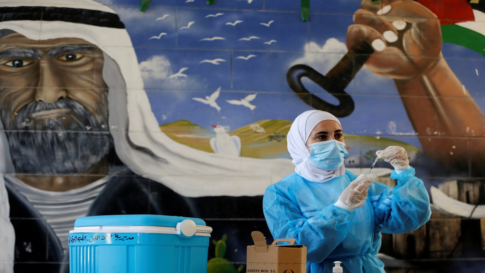 ممرضة فلسطينية تستعد لإعطاء جرعة من اللقاح المضاد لكورونا مع بدء العام الدراسي في مدرسة بالقرب من الخليل في الضفة الغربية المحتلة. 01/09/2021. (موسى قواسمي/ رويترز)