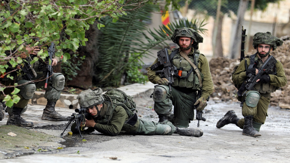 جنود من قوات الاحتلال الإسرائيلي يوجهون أسلحتهم تجاه فلسطينيين في الضفة الغربية المحتلة. (رويترز)