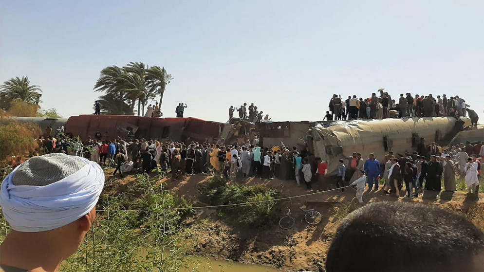 تجمع حول حطام قطارين اصطدما في منطقة طهطا بمحافظة سوهاج ، على بعد نحو 460 كيلومترًا (285 ميلًا) جنوب العاصمة المصرية القاهرة. (أ ف ب)
