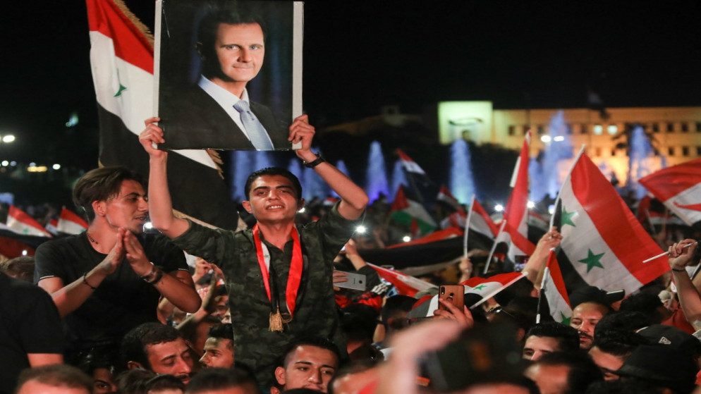 شاب سوري يرفع صورة الرئيس الذي أعيد انتخابه بشار الأسد مساء الخميس 27 أيار/مايو 2021 في العاصمة دمشق. (أ ف ب)
