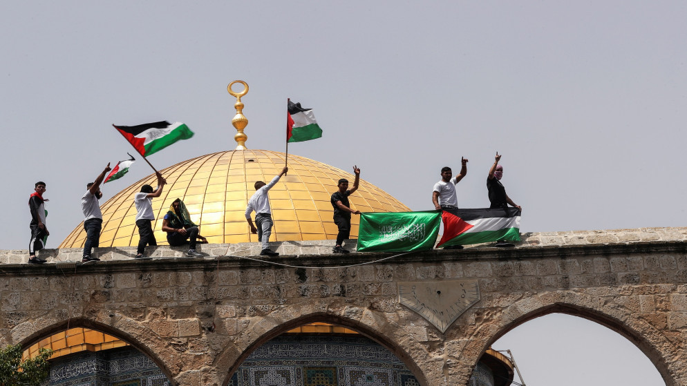 فلسطينيون يرفعون أعلامًا في باحة المسجد الأقصى، 21 مايو/أيار 2021. (رويترز)
