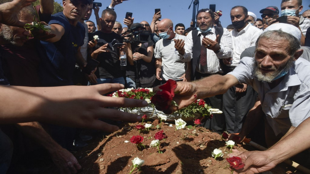 جزائريون يضعون الورود على قبر الرئيس السابق عبد العزيز بوتفليقة خلال جنازته في مقبرة العليا بالعاصمة الجزائر .19 سبتمبر/أيلول 2021.(أ ف ب)