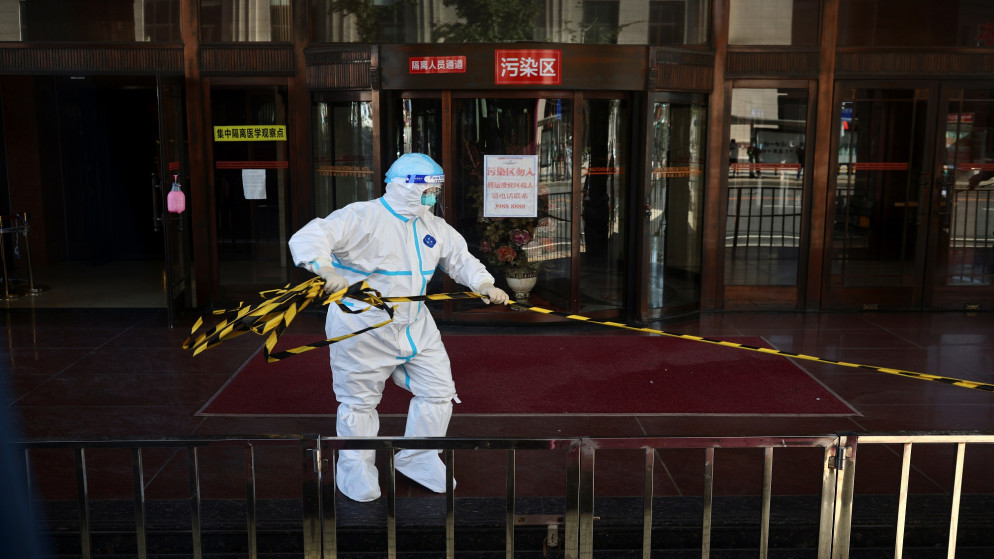 عامل في القطاع الصحي في الصين يزيل حبلا أمام فندق خصص للحجر الصحي. (رويترز)