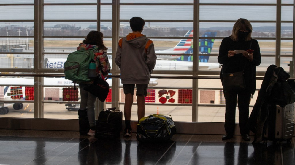 مسافرون يشاهدون الطائرات على مدرج المطار بالقرب من مكاتب تسجيل الوصول في مطار رونالد ريغان الدولي في واشنطن العاصمة، 27 ديسمبر 2021. (أ ف ب)