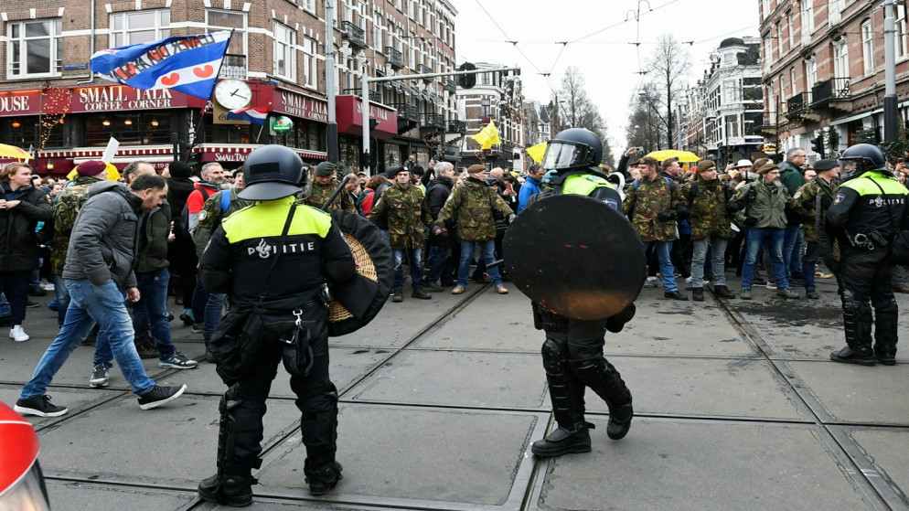 يقف ضباط الشرطة في حراسة معارضي القيود المفروضة في هولندا لاحتواء انتشار فيروس كورونا، أمستردام، هولندا، 2 كانون الثاني/يناير 2022. (رويترز)