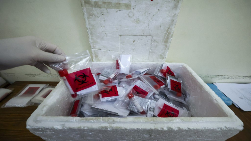 عامل صحي فلسطيني يجمع عينات مسحة من الأنف لاختبار فيروس كورونا COVID-19 في قرية دورا غرب الخليل في الضفة الغربية المحتلة .1 يناير 2022. (أ  ف ب)