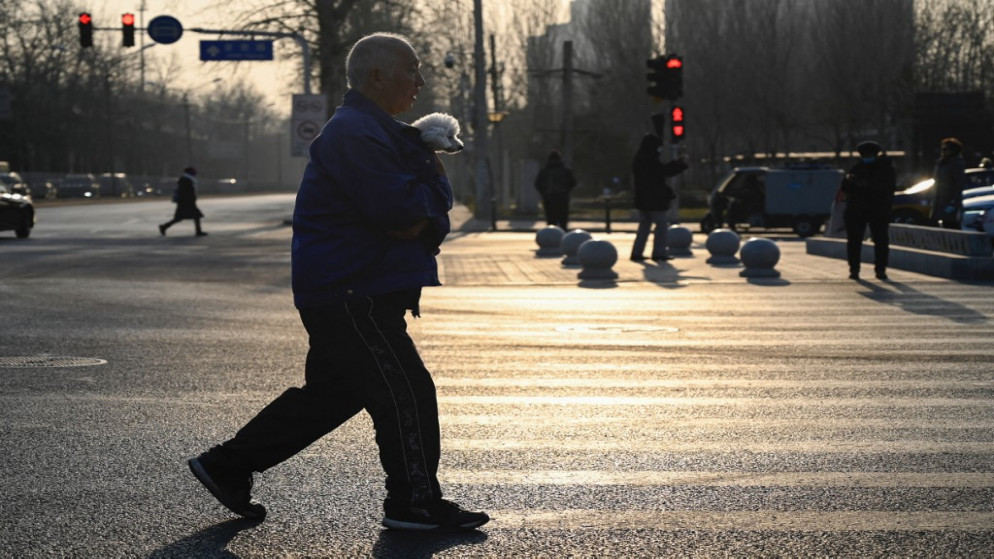 رجل يسير على طول الطريق مع كلب داخل سترته في بكين .4 يناير 2022.(أ ف ب)