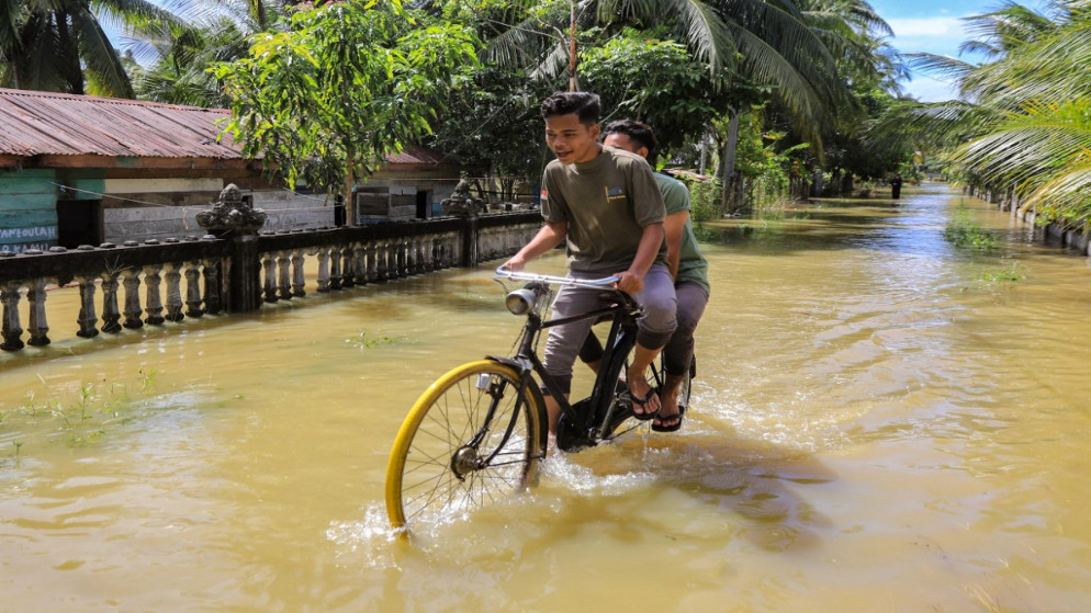 دراجة في شارع غمرته المياه في منطقة جامبونغ ميوناساه في شمال آتشيه .4 يناير 2022.(أ ف ب)