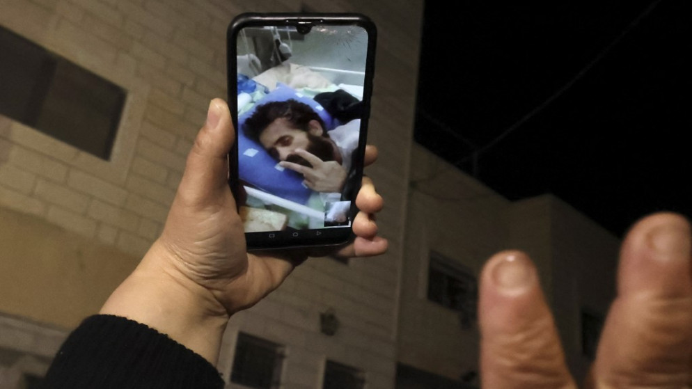 فلسطينيون يتحدثون في مكالمة فيديو مع الأسير الفلسطيني هشام أبو هواش، وهو يرقد في المستشفى، بعد إنهاء إضرابه عن الطعام ،4 كانون الثاني/يناير 2022. (أ ف ب)