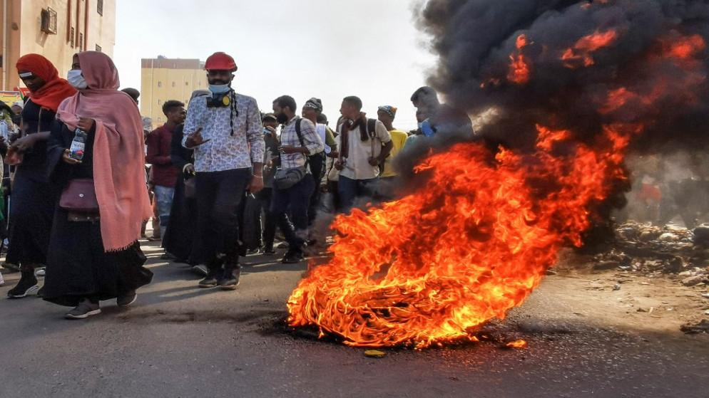 متظاهرون سودانيون يحتشدون ضد الجيش يسيرون أمام الإطارات المحترقة في العاصمة الخرطوم.6 كانون الثاني/ يناير 2022.(أ ف ب)