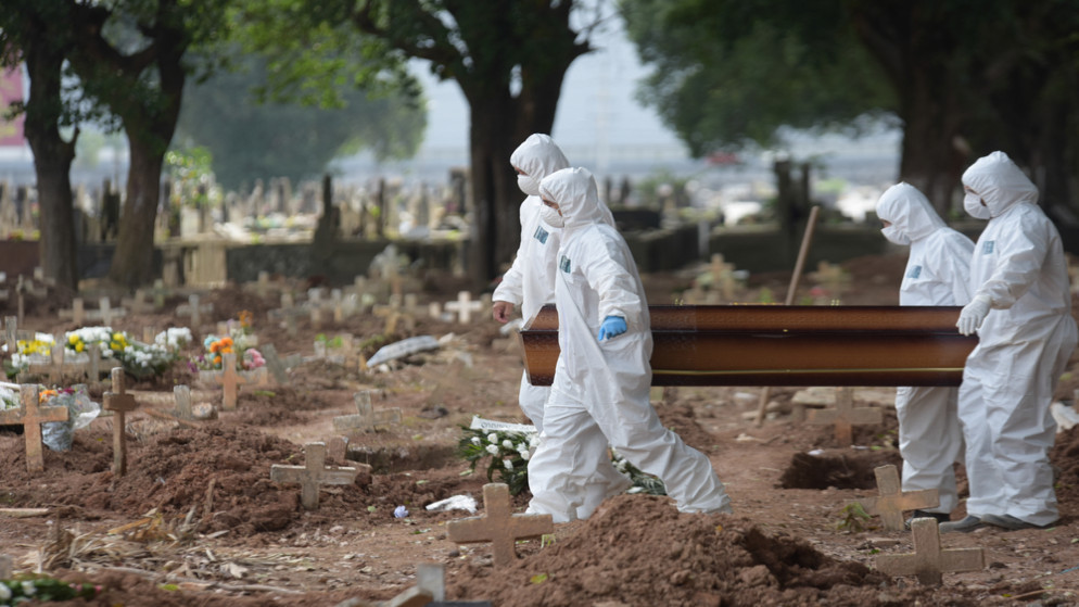 عمال ينقلون جثة شخص مات بسبب فيروس كورونا، في مقبرة الكاغو في ريو دي جانيرو، البرازيل. (رويترز )