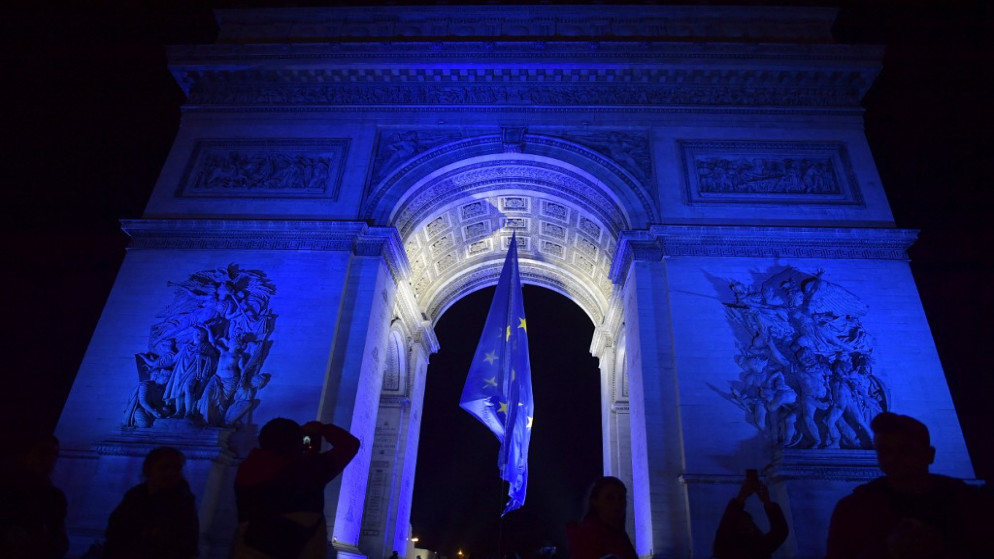 قوس النصر المضاء باللون الأزرق وتحته علم الاتحاد الأوروبي للاحتفال بالرئاسة الفرنسية للاتحاد الأوروبي. (أ ف ب)