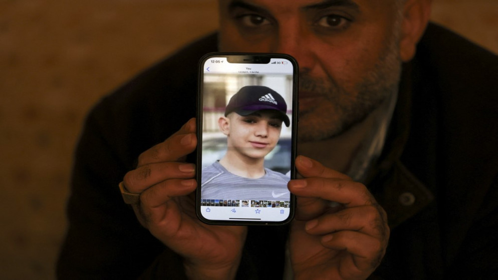 معمر نخلة والد الفتى الفلسطيني أمل نخلة وهو يحمل صورة ابنه المريض والمعتقل إداريا في سجن إسرائيلي. (أ ف ب)