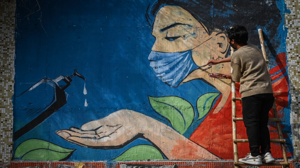 عامل يرسم فتاة ترتدي كمامة للحماية من فيروس كورونا، الهند. (أ ف ب)