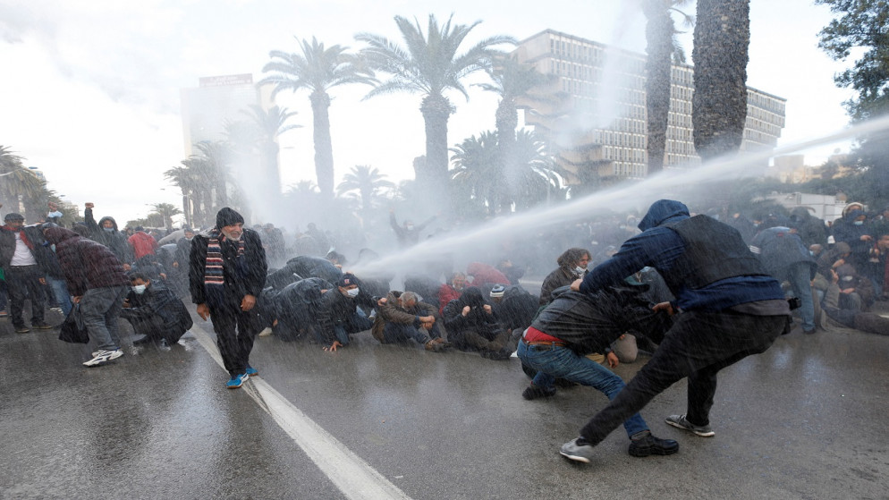 إصابة متظاهرين بخراطيم المياه، في تونس العاصمة، تونس ، 14 كانون الثاني/يناير  2022. (رويترز)