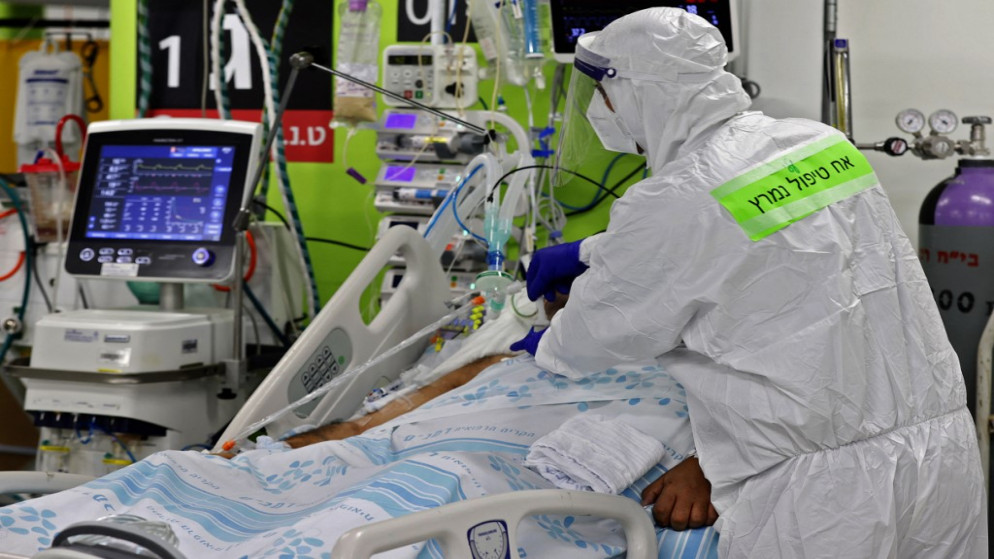 أحد أفراد الطاقم الطبي يرتدي ملابس واقية من كورونا خلال العناية بمصاب بالفيروس بمرفق طبي في حيفا.11 أكتوبر 2020.(أ ف ب)