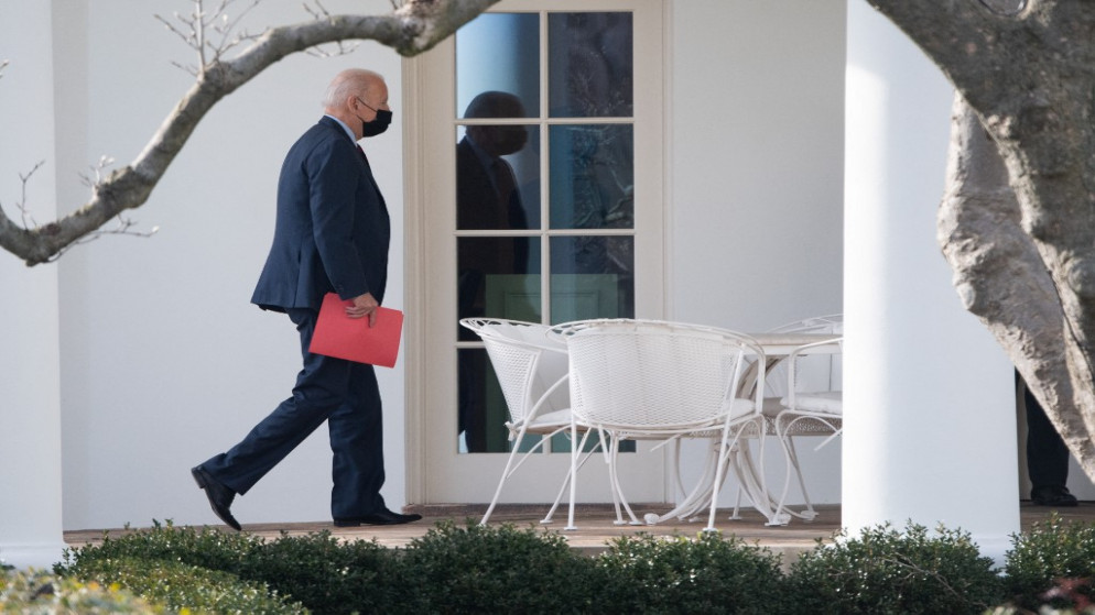 يحمل الرئيس الأميركي جو بايدن ملفًا أحمر اللون أثناء توجهه إلى المكتب البيضاوي في البيت الأبيض في واشنطن العاصمة.25 يناير 2022.(أ ف ب)