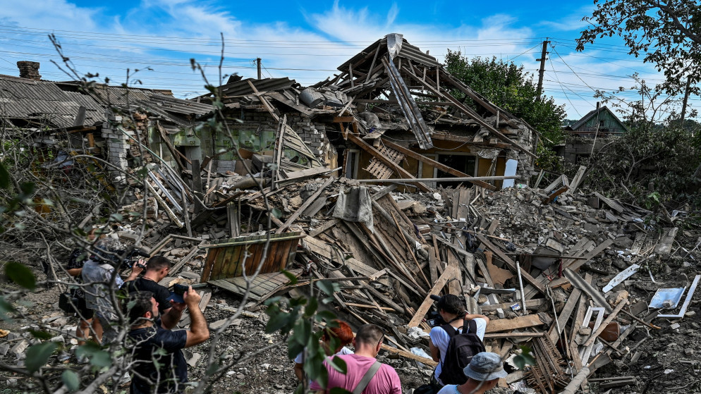 أشخاص يقفون بجوار منزل سكني دمرته ضربة صاروخية روسية في كوشوهوم في منطقة زابوروجيا الأوكرانية، 10 آب/ أغسطس، 2022. (رويترز)