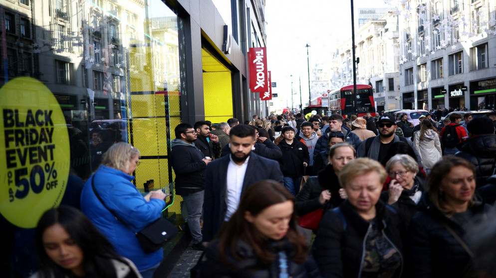 أشخاص يمشون أمام لافتات الجمعة السوداء في نوافذ المتاجر خلال الجمعة السوداء في لندن 25 تشرين الثاني/نوفمبر 2022. (رويترز)