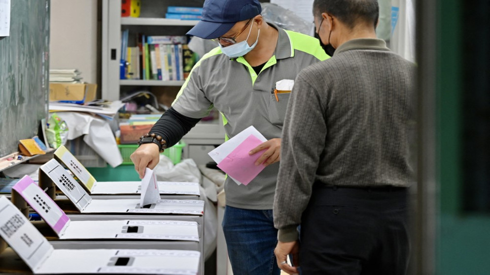 رجل يسقط بطاقة اقتراع في مركز اقتراع أثناء التصويت لانتخابات رئاسة البلدية في مدينة تايبيه الجديدة .26 نوفمبر 2022.(أ ف ب)