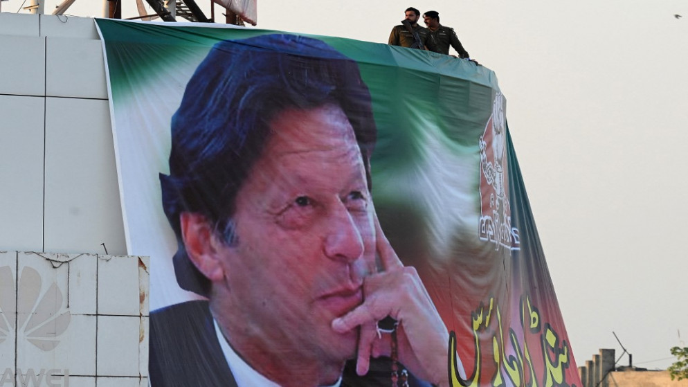 رجال الشرطة يقفون في حراسة فوق صورة عملاقة لرئيس الوزراء الباكستاني السابق عمران خان خلال تجمع مناهض للحكومة في روالبندي في 26 نوفمبر 2022.(أ ف ب)