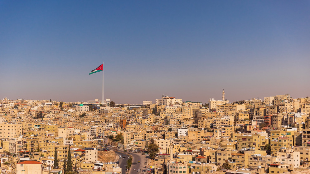 منظر عام لمبانٍ في مدينة عمّان ويظهر معها علم الأردن. (shutterstock)