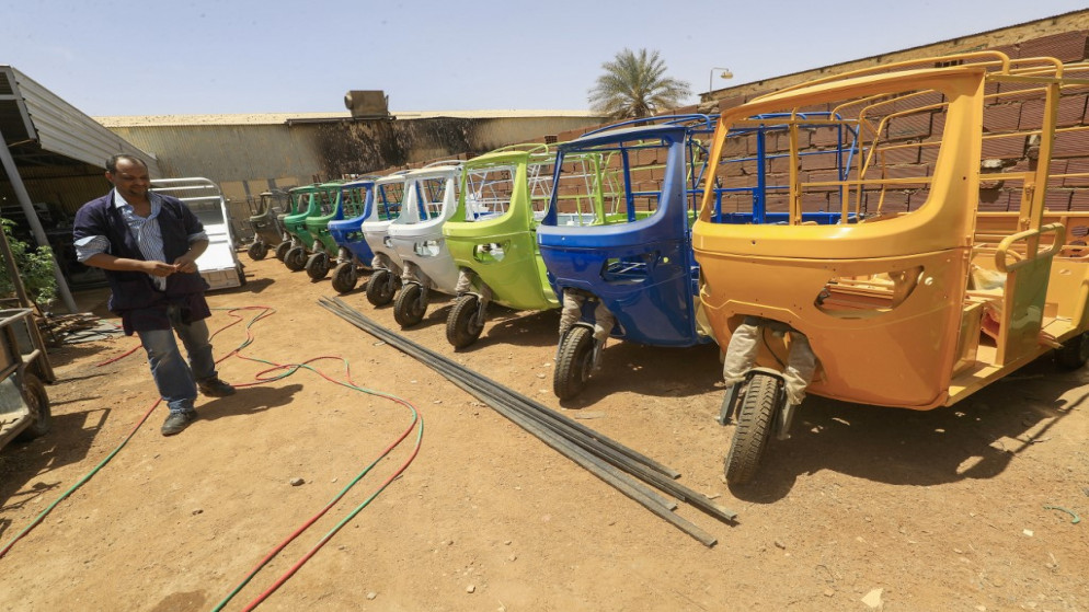 عمال يجمعون "توك توك" كهربائي في مصنع الشهاب في العاصمة السودانية الخرطوم. 19/04/2022. (أشرف الشاذلي / أ ف ب)