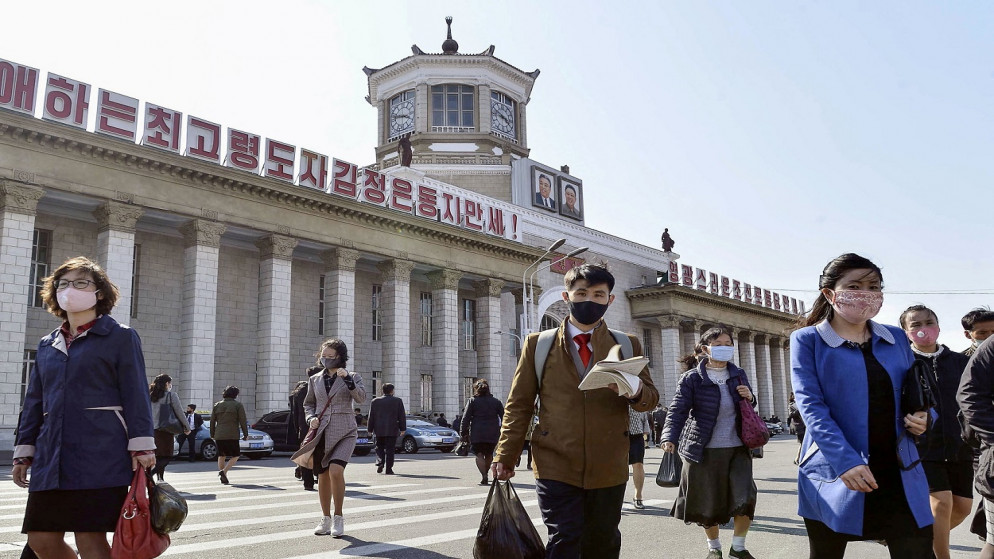 أشخاص يرتدون أقنعة واقية يسيرون وسط مخاوف بشأن مرض فيروس كورونا، أمام محطة بيونغ يانغ في بيونغ يانغ، كوريا الشمالية، 27 أبريل 2020. (رويترز)