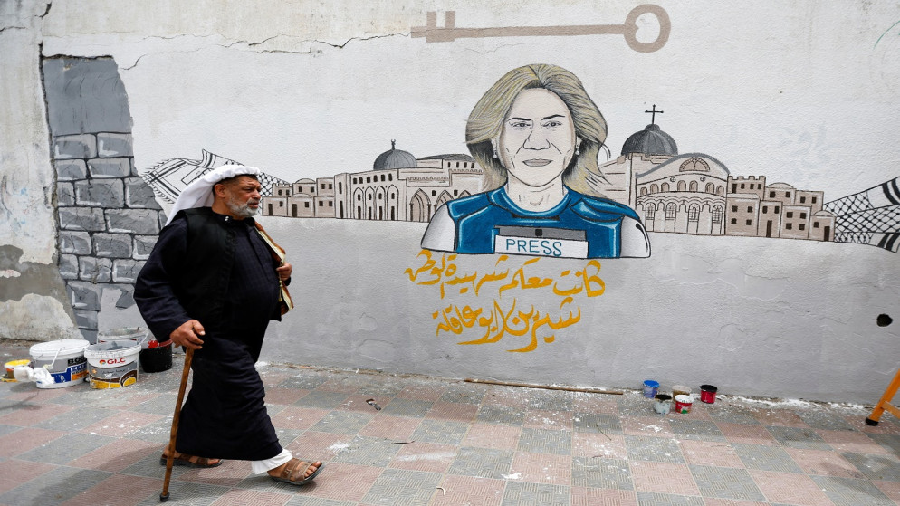رجل يسير أمام جدارية لشيرين أبو عاقلة، في خانيونس جنوب قطاع غزة، 14 مايو 2022. (رويترز)