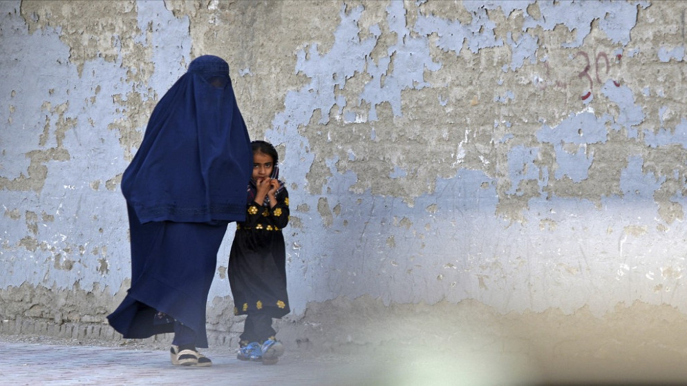 امرأة ترتدي البرقع تمشي مع فتاة على طول أحد شوارع كابول .7 أيار/مايو 2022.(ا ف ب)
