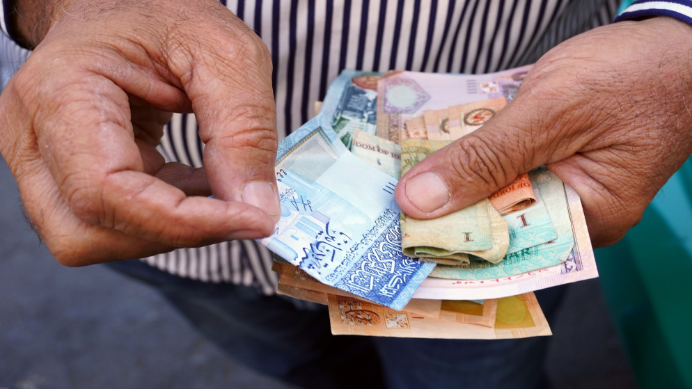 شخص يحمل أموالا بعملة الدينار الأردني. (shutterstock)
