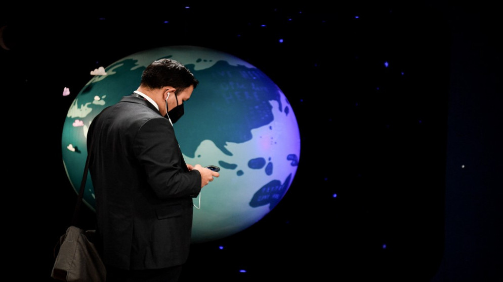 رجل يقف أمام مجسم للكرة الأرضية في مؤتمر الأمم المتحدة لتغير المناخ COP26 في غلاسكو باسكتلندا. 31/10/2021. (ألين جوكارد/ أ ف ب)