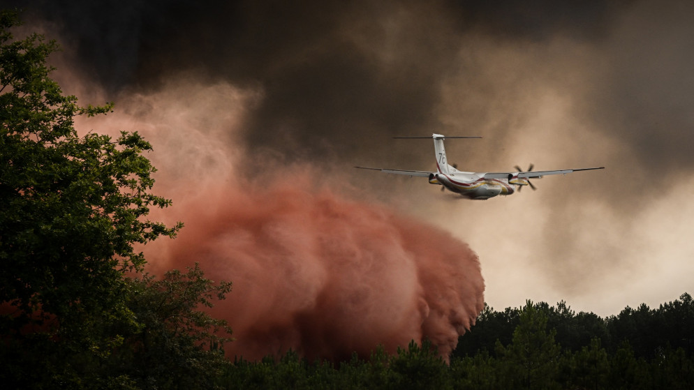 طائرة إطفاء حريق ترش مثبطات الحريق فوق الأشجار أثناء حريق غابات بالقرب من سان ماجني جنوب غرب فرنسا. 11 أغسطس 2022. (أ ف ب)