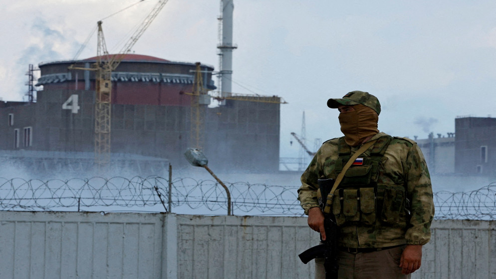 جندي يرفع العلم الروسي على زيه العسكري يقف قرب محطة زابوروجيا للطاقة النووية في سياق الصراع الأوكراني الروسي. 04/08/2022. (رويترز)