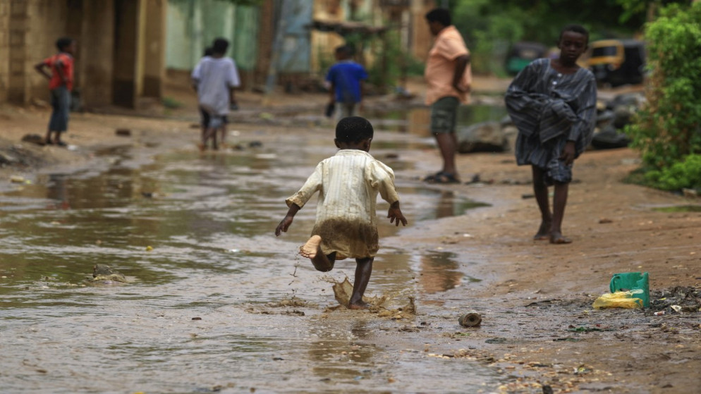 طفل يجري في مياه الفيضانات بعد هطول أمطار غزيرة في العاصمة السودانية الخرطوم، 13 آب/ أغسطس2022. (أ ف ب)