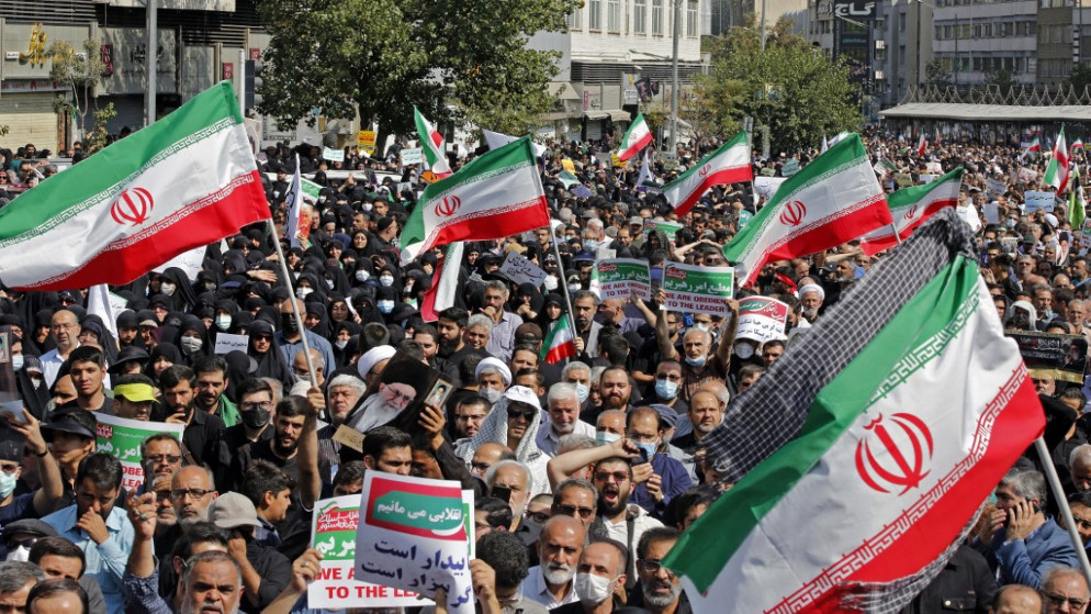 إيرانيون يلوحون بالعلم الوطني وهم يسيرون خلال مسيرة مؤيدة للحجاب في العاصمة طهران في 23 سبتمبر 2022. (أ ف ب)