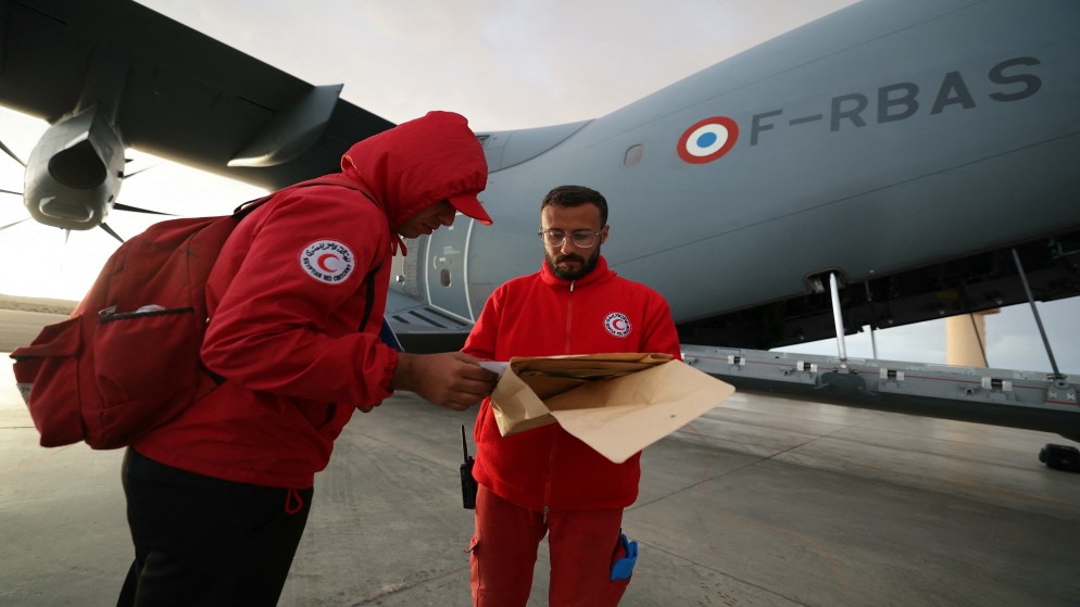 شخص في الهلال الأحمر المصري قرب طائرة فرنسية تنقل مساعدات إلى قطاع غزة. (أ ف ب)