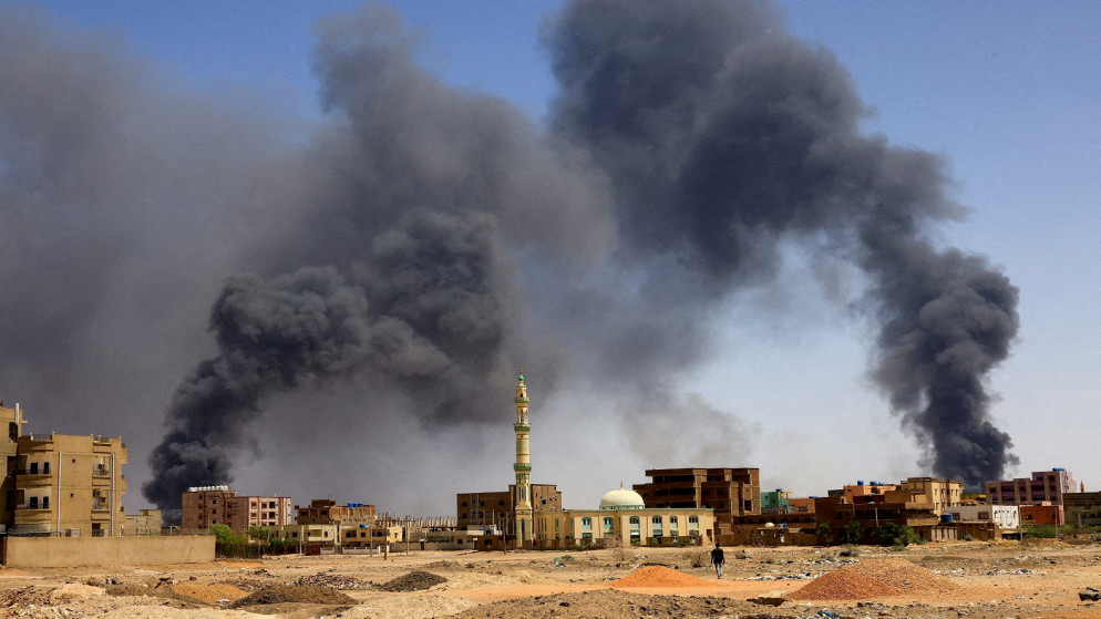 رجل يسير بينما يتصاعد الدخان فوق المباني بعد قصف جوي خلال اشتباكات في السودان، 1  أيار 2023. (رويترز)