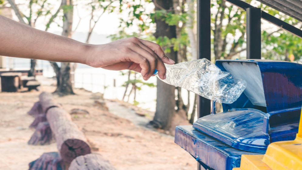 صورة توضيحية لشخص يرمي عبوة بلاستيك في حاوية نفايات صلبة. (istockphoto)